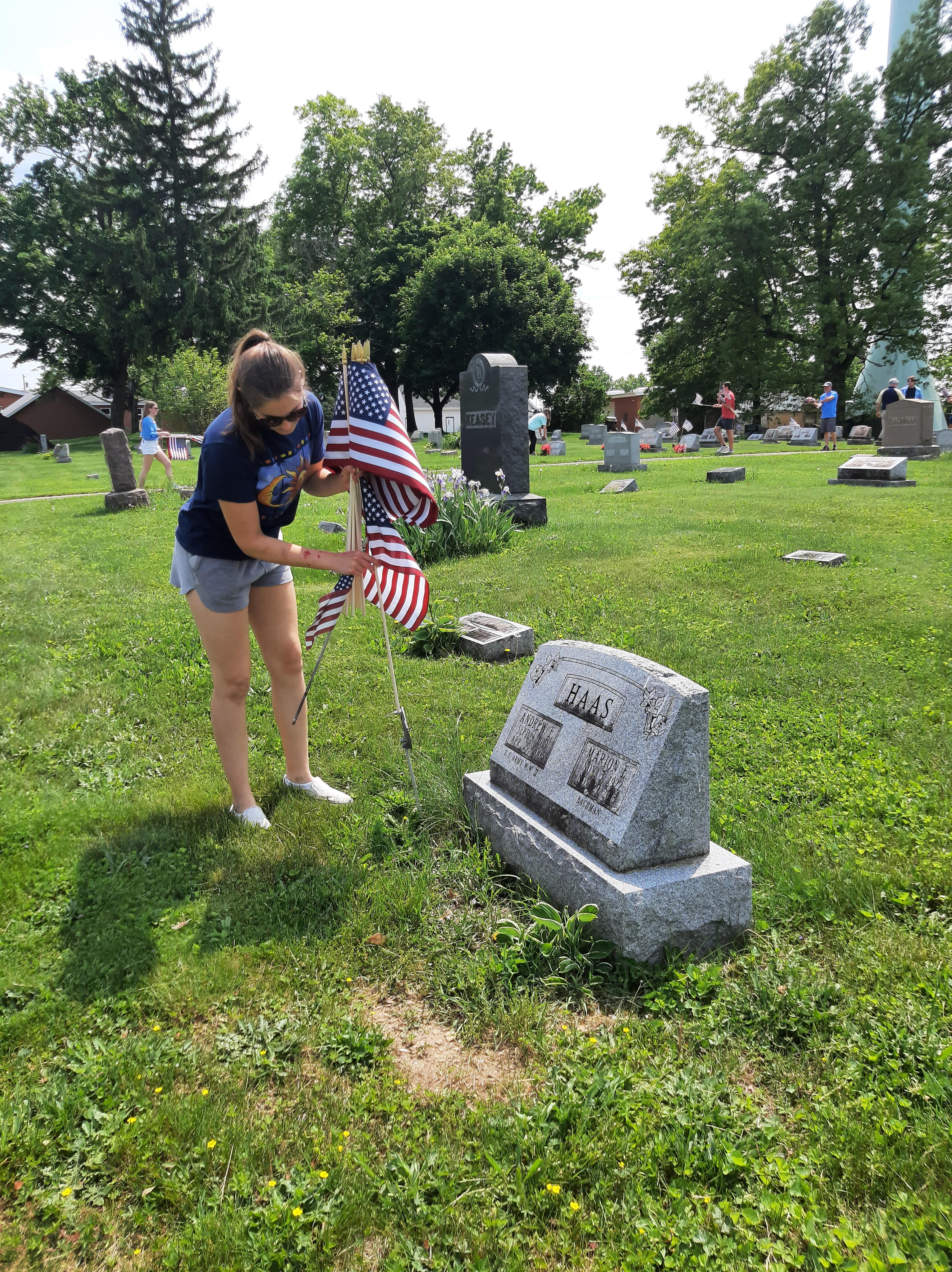 pic of a student replacing a flag on a grave