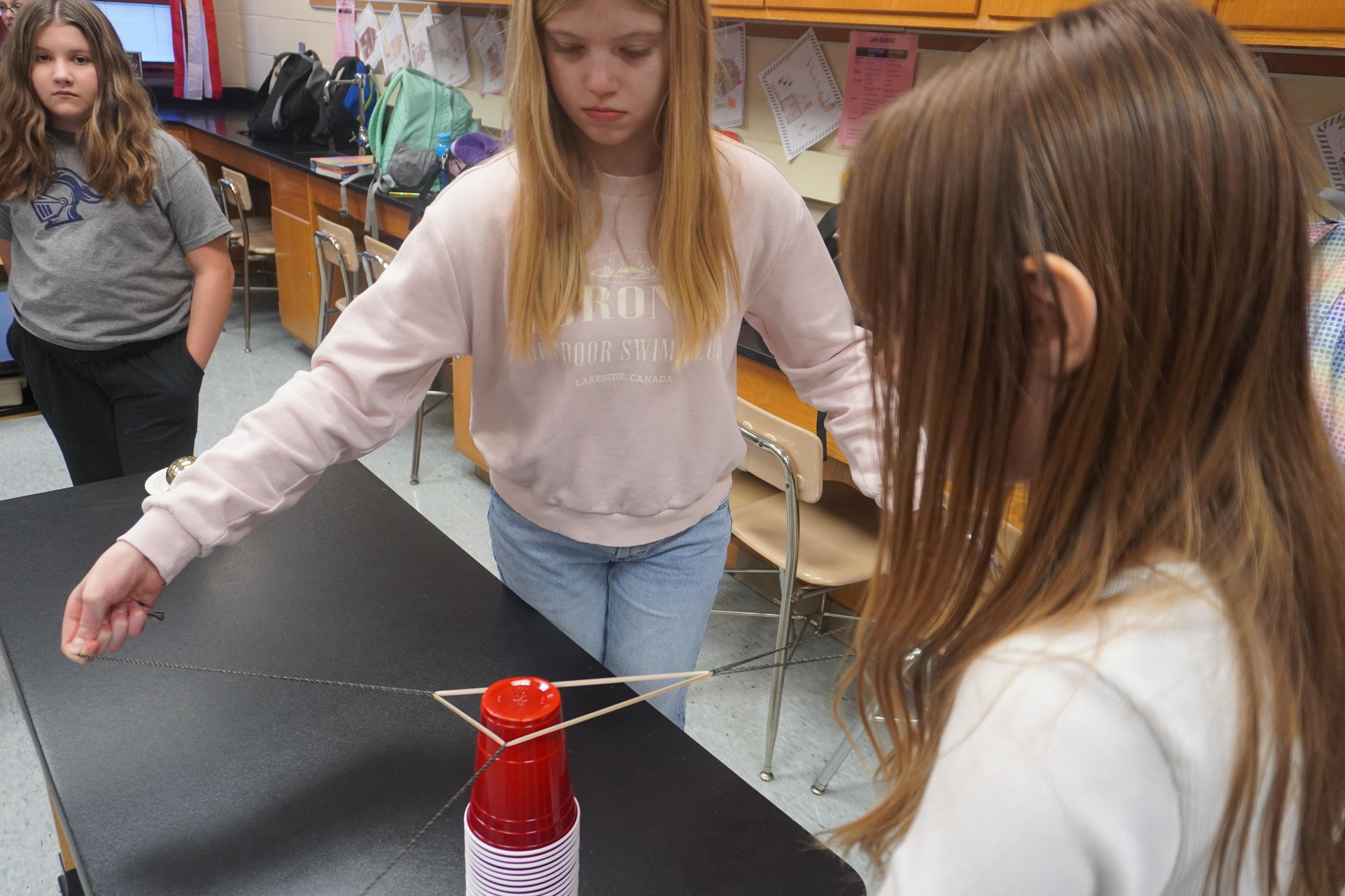 students using string to move cups